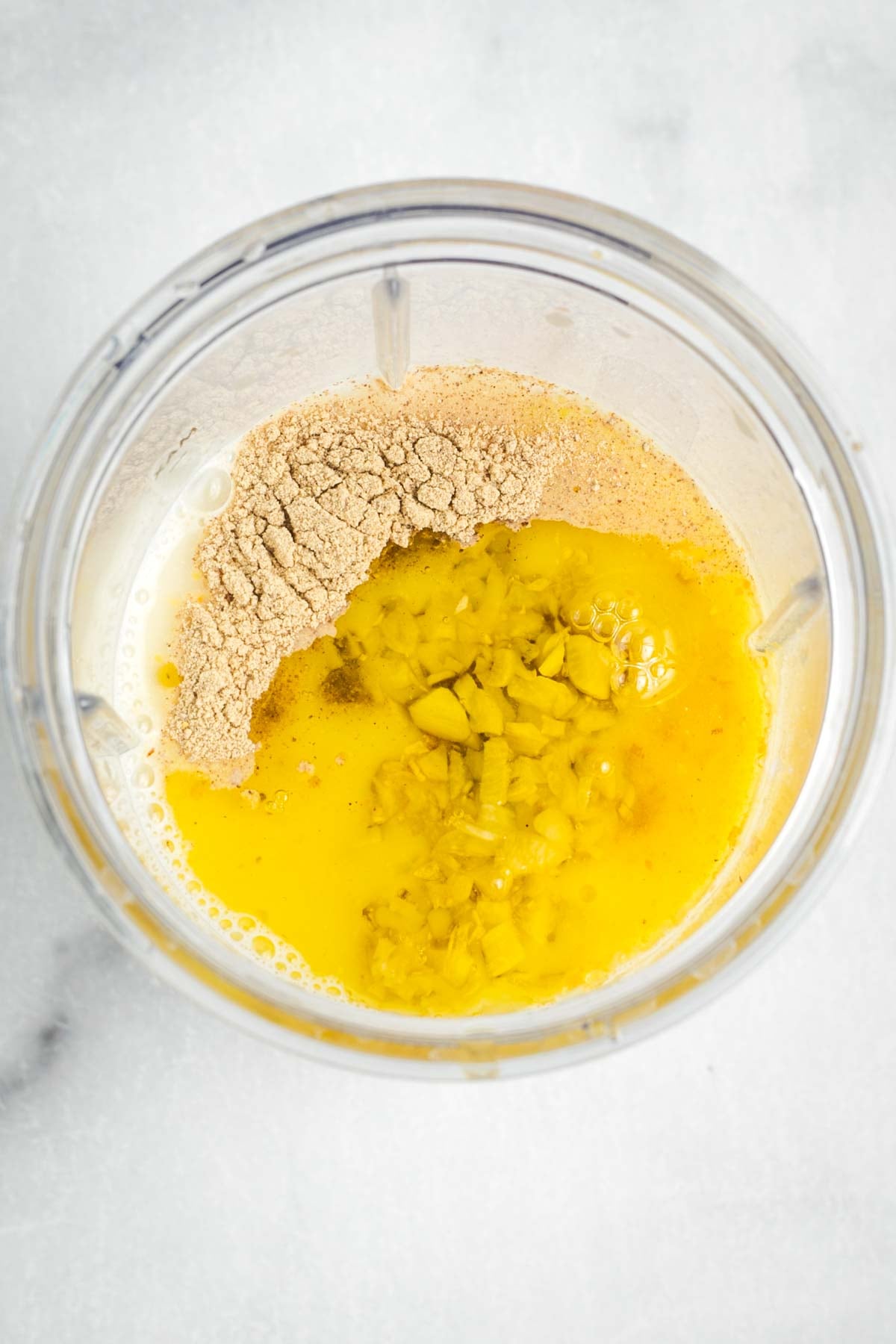 Ingredients in a blender cup: nutritional yeast, garlic, broth are visible.