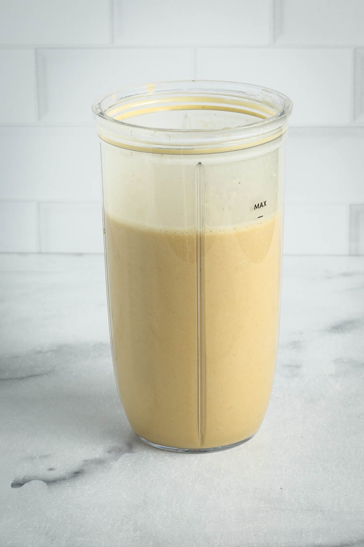 Blender cup filled with creamy beige sauce.