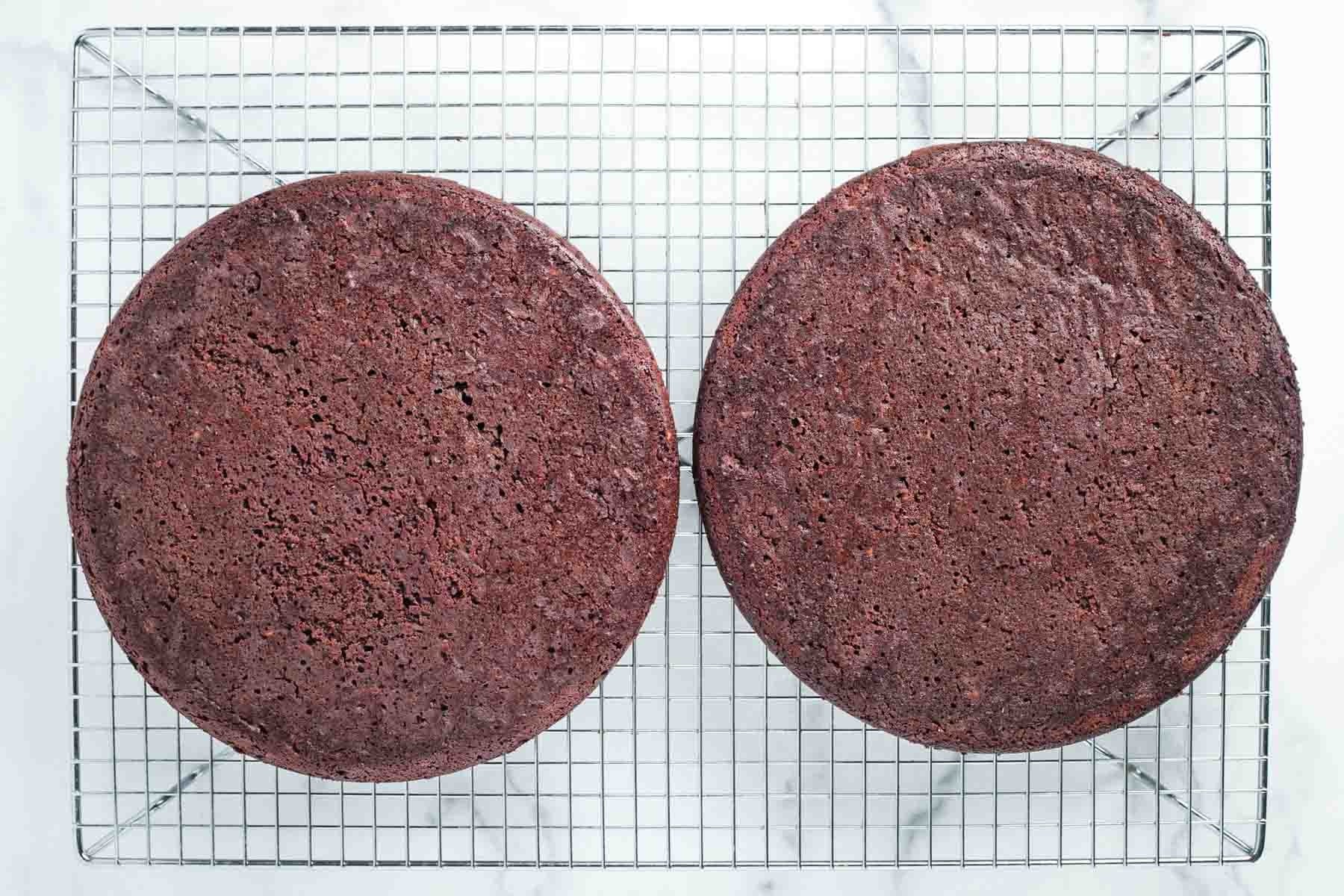 Two round chocolate cakes cooling on a wire rack.