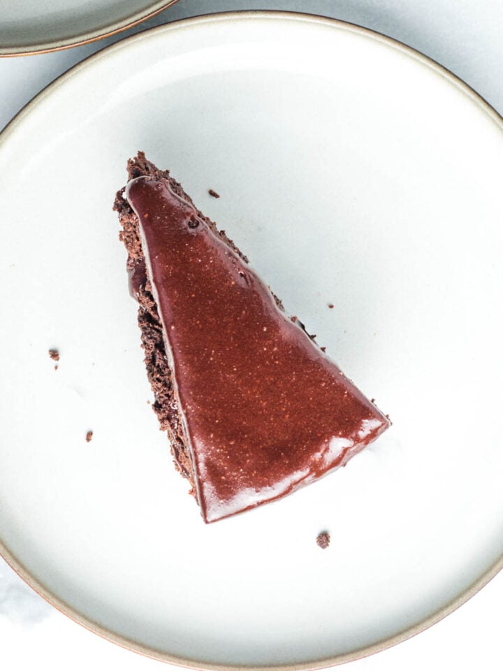 Slice of chocolate cake with chocolate frosting on a white plate.