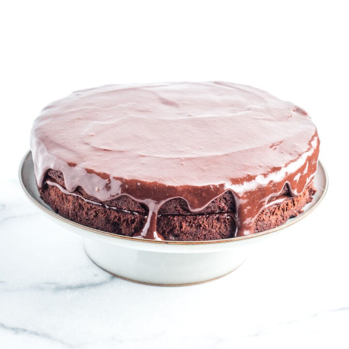 Two layers of chocolate cake with chocolate frosting in between, on top and dripping down the sides.