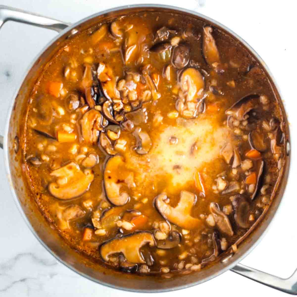 White slurry ina pot of mushroom barley soup. 