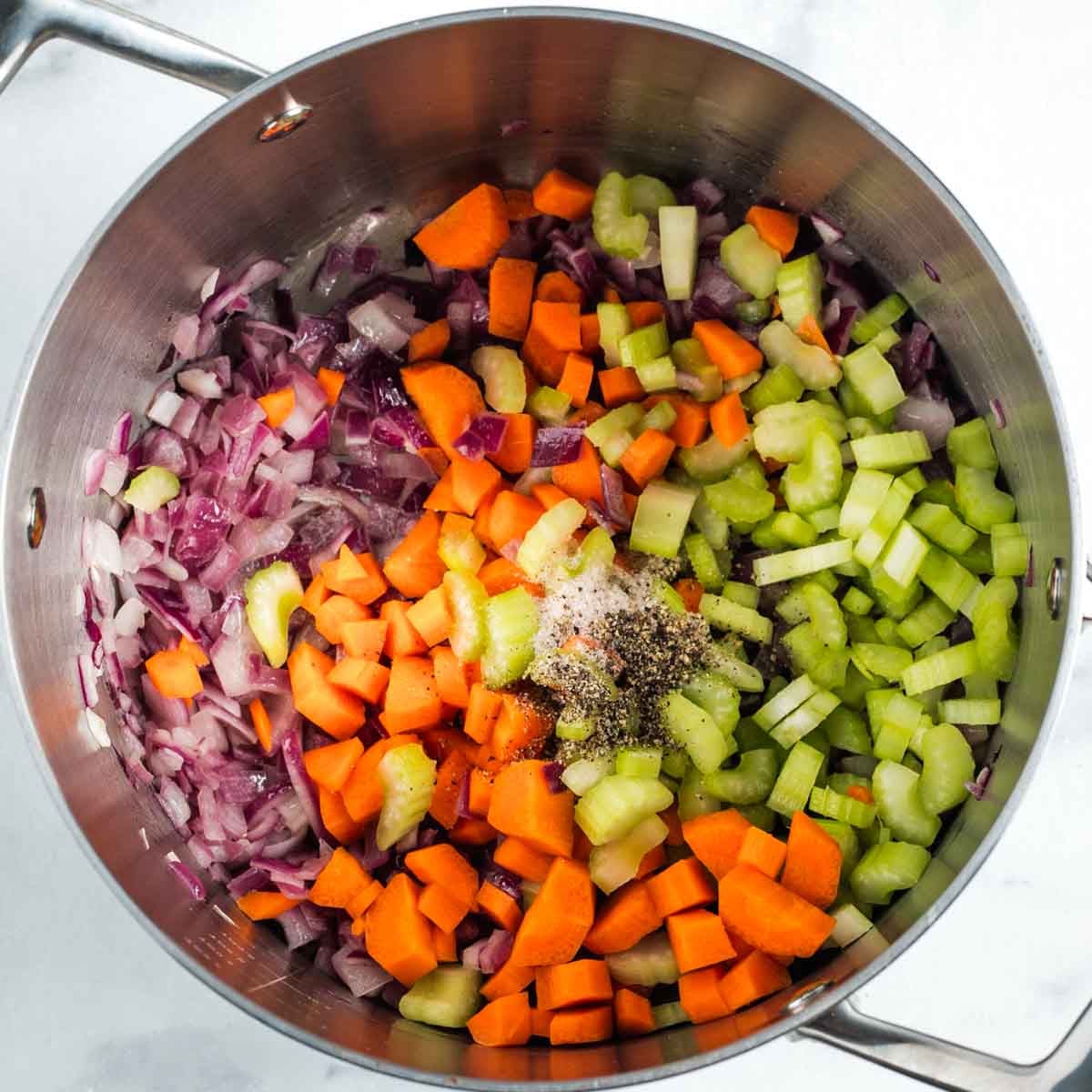 Soup pot with diced red onion, celery and carrot, plus salt and pepper. 