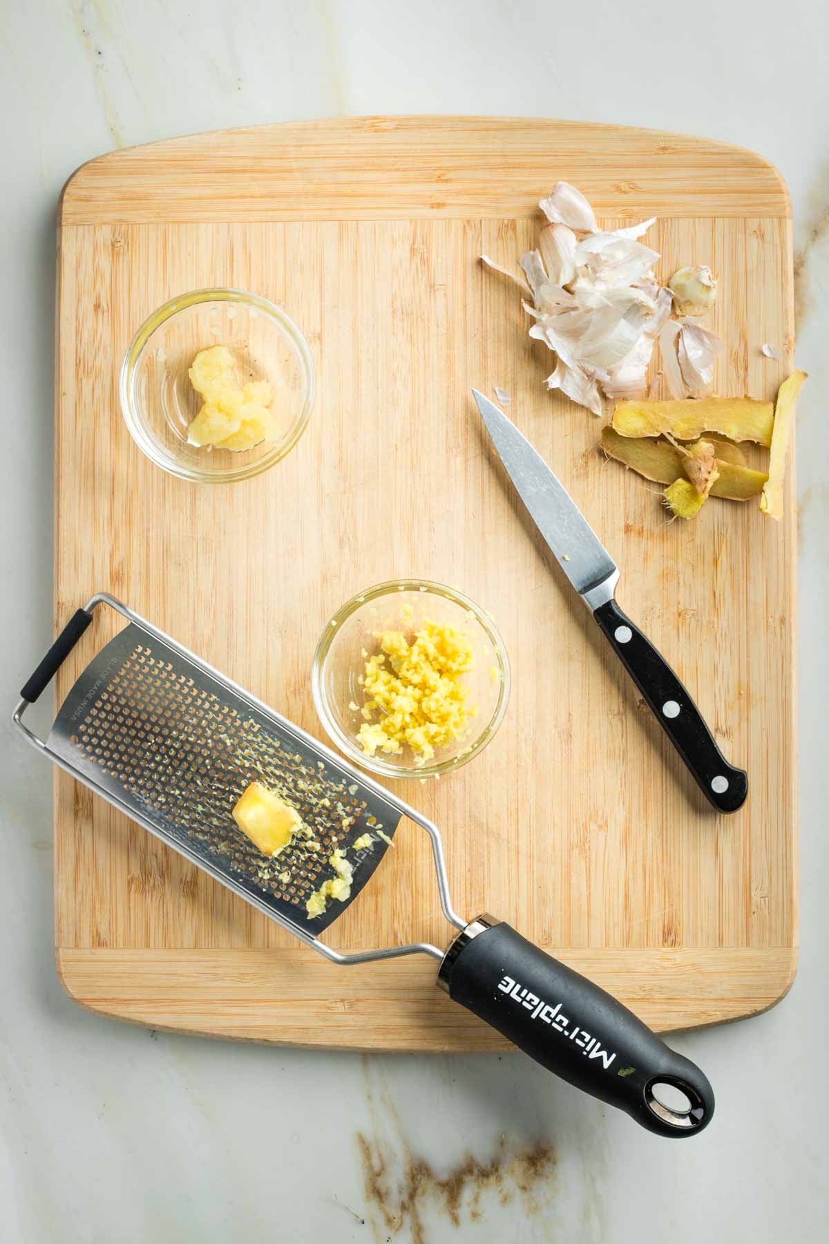 Grated garlic and ginger using a microplane, in small glass dishes.