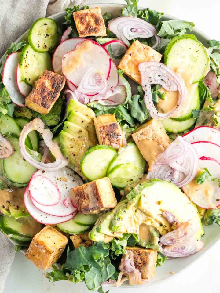 Bed of greens topped with slices of cucumber, shallot, avocado and crisp cubes of tofu drizzled with sesame ginger dressing.