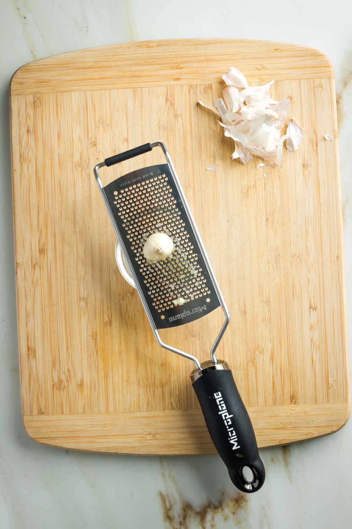 Grating fresh, peeled garlic on a microplane.