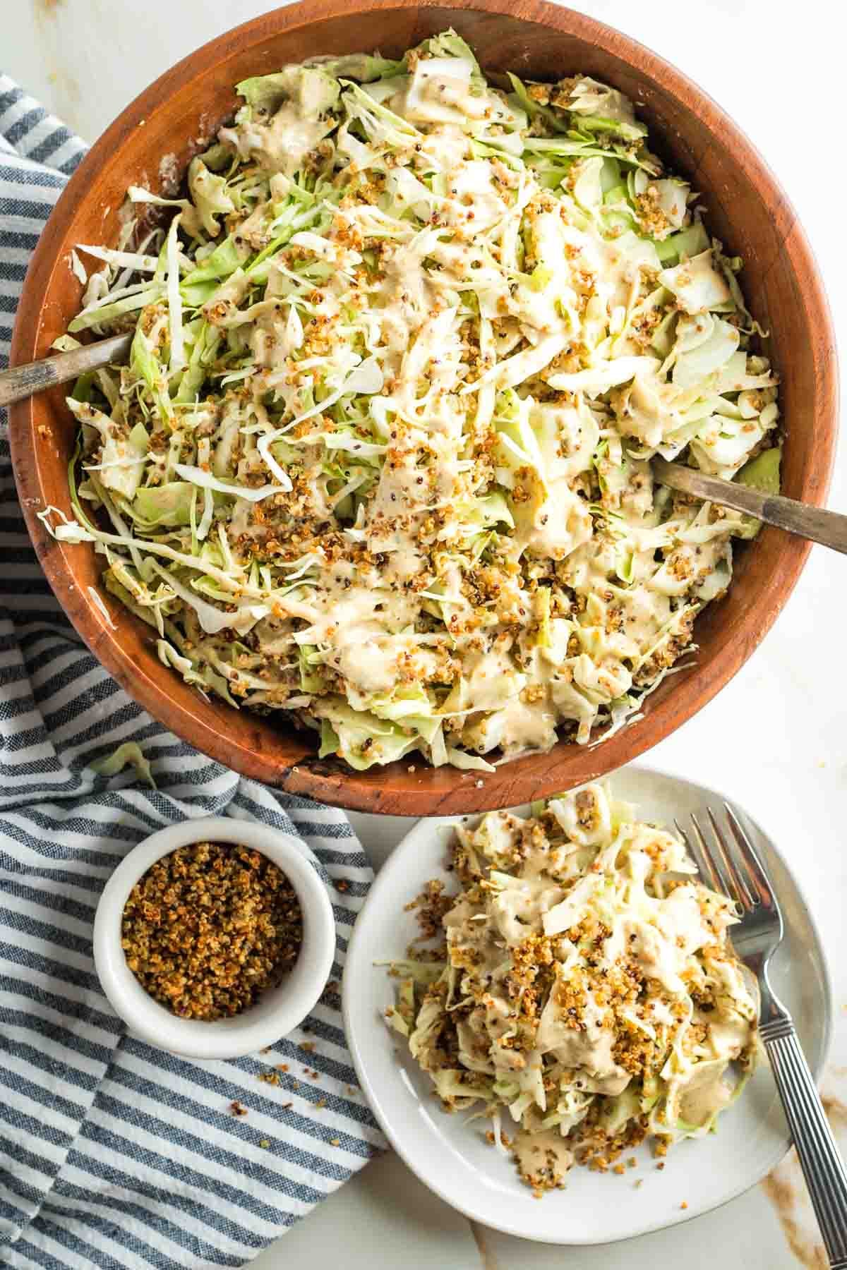 Large bowl of cabbage salad with caesar dressing and crispy quinoa, plus a small plate of same. 