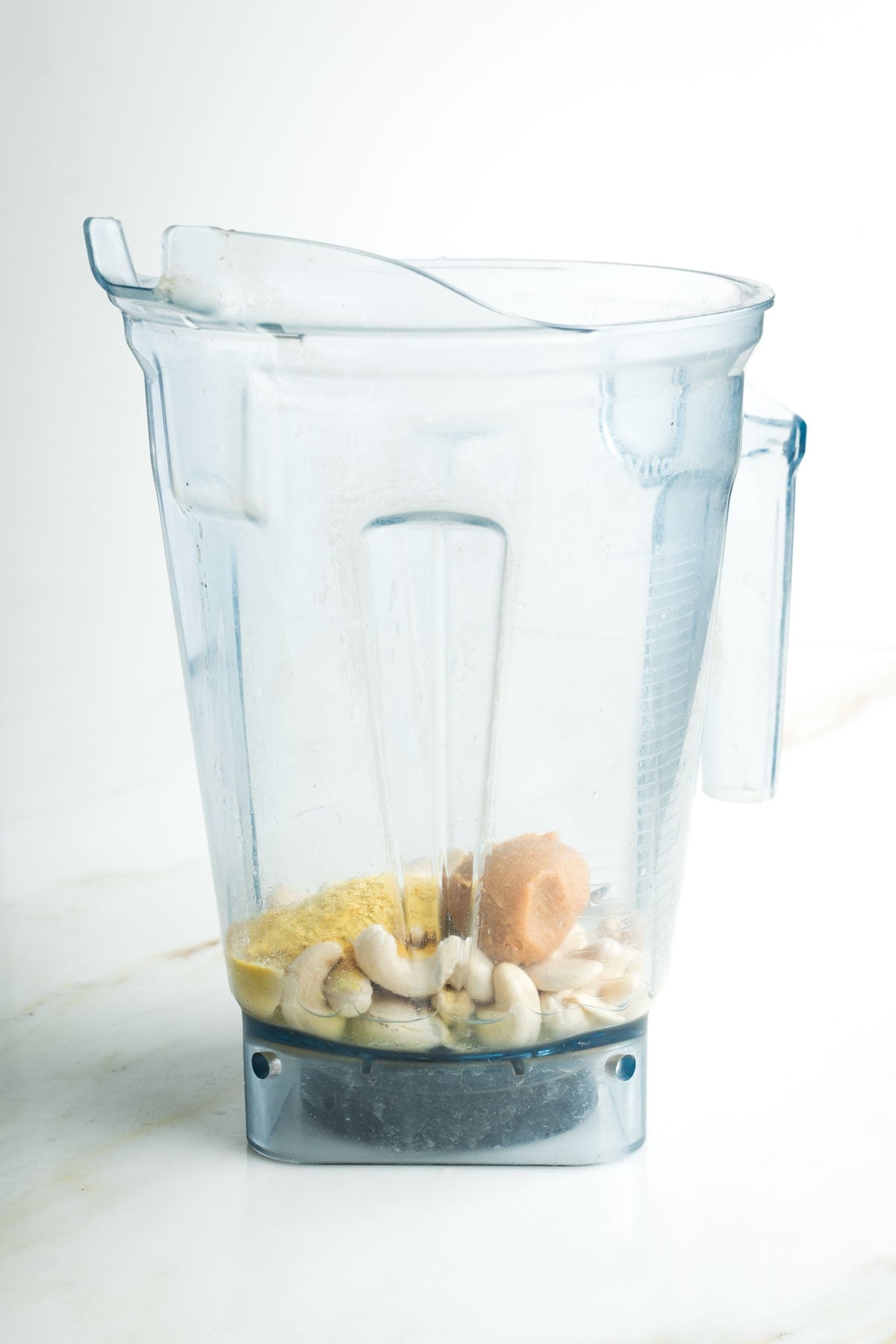 Vitamix pitcher with cashews, miso, nutritional yeast and water. 