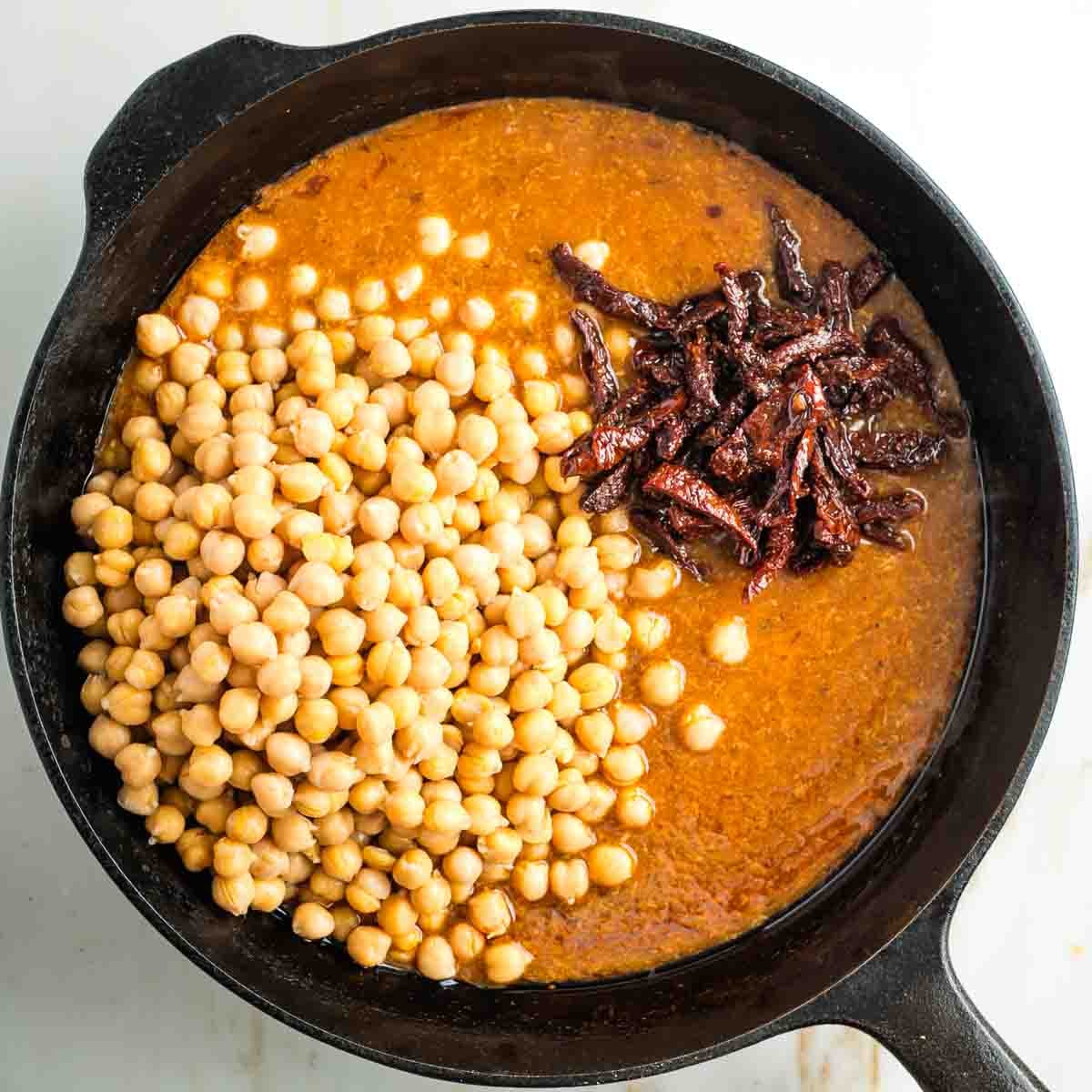 Light tomato sauce in a skillet with chickpeas and sun dried tomatoes.