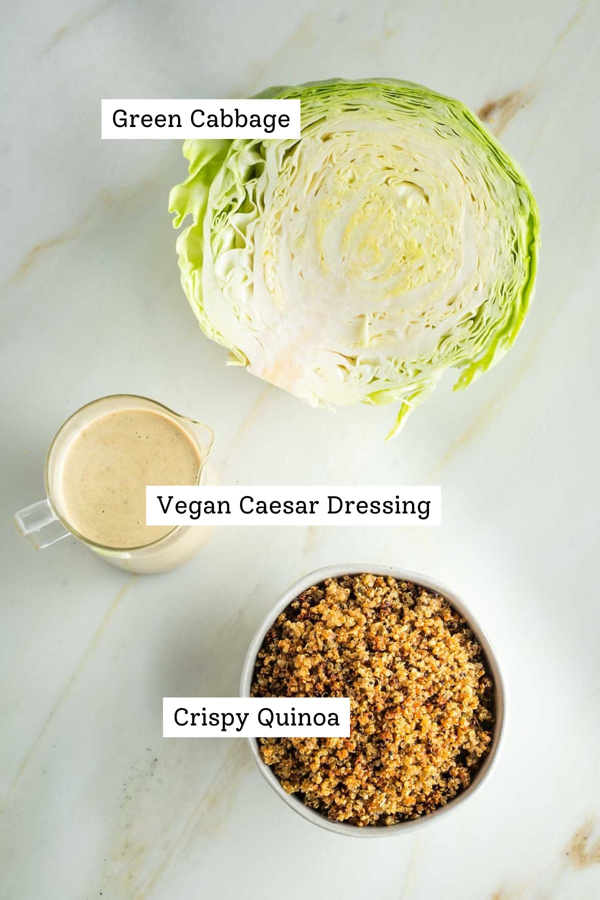 Half head of green cabbage, small pitcher of dairy-free caesar dressing and a bowl of crispy quinoa. 