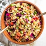 Tossing together a vibrant pasta salad with colorful veggies in a wooden bowl.