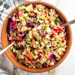 Tossing together a vibrant pasta salad with colorful veggies in a wooden bowl.