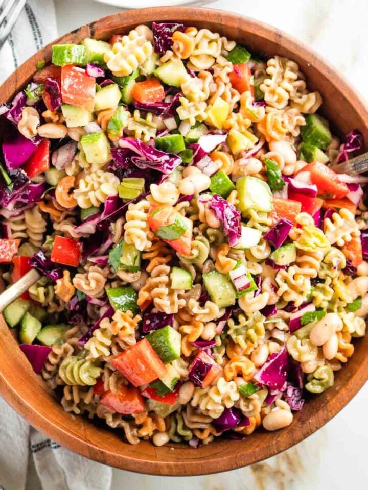 Tossing together a vibrant pasta salad with colorful veggies in a wooden bowl.