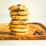 Stack of chocolate chip cookies on a wooden board.