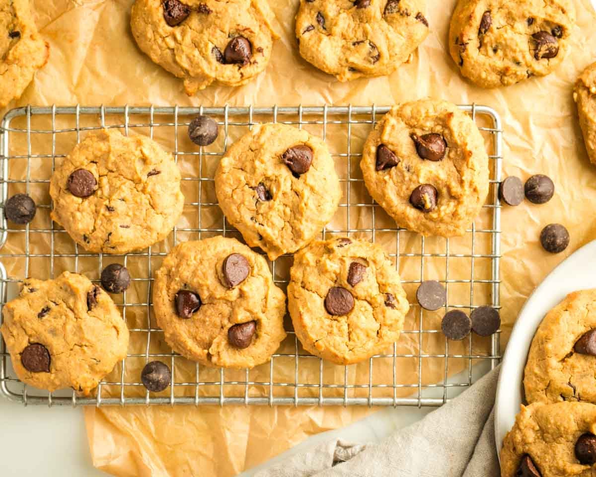Chocolate chip cookies on a small wire rack atop a piece of parchment paper. 