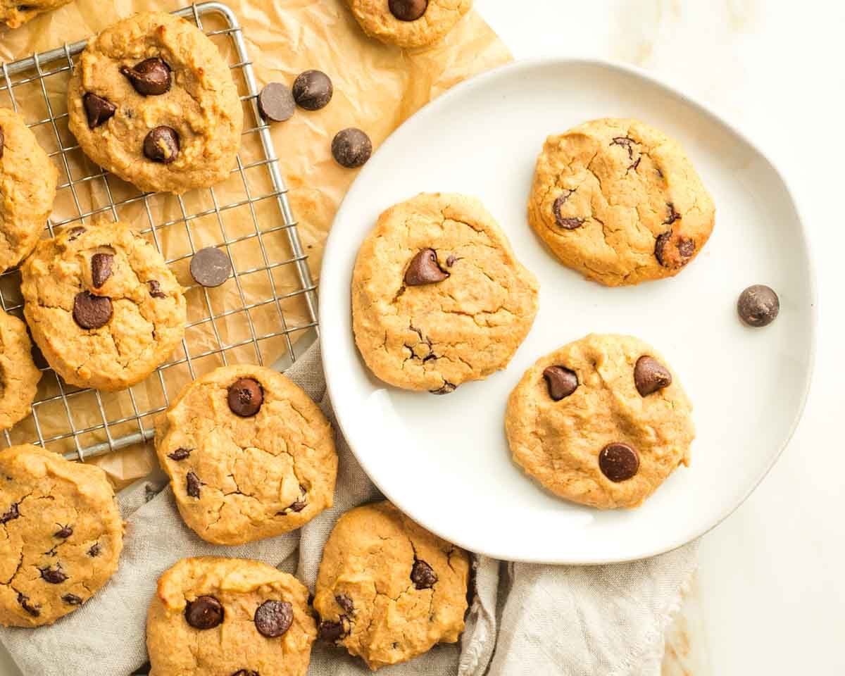 Chocolate chip cookies on a plate, and cooling on a wire rack.