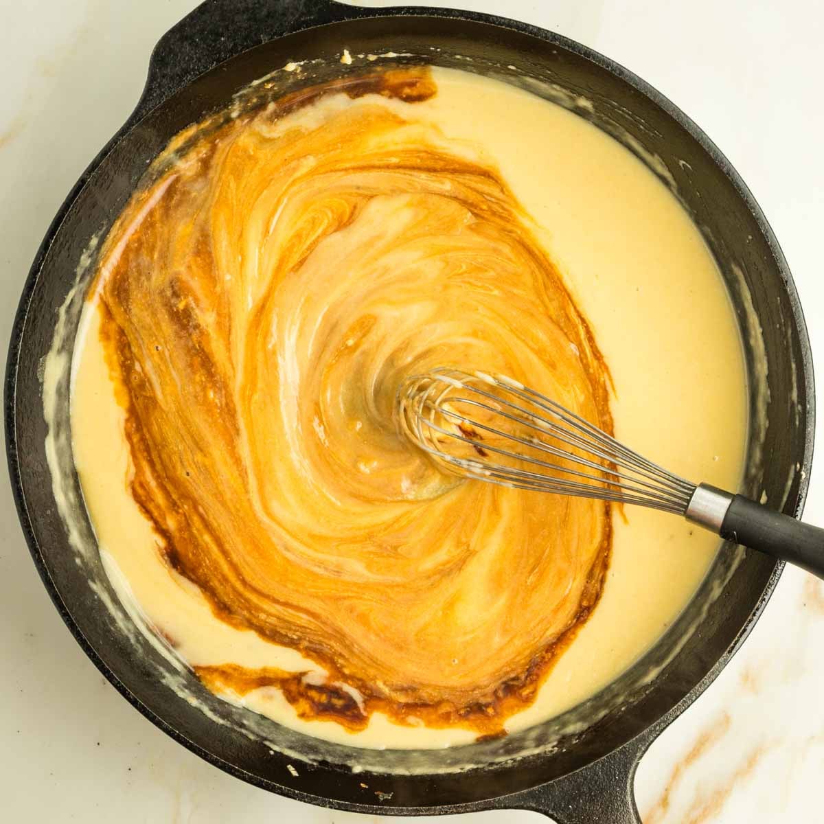 Whisking tamiri into a yellow sauce in a cast iron creates a swirly bit of art.