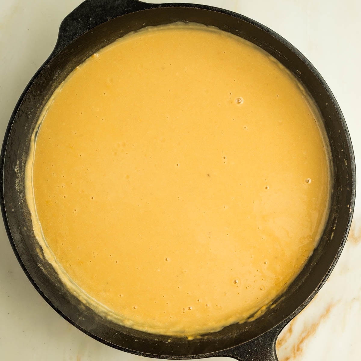 Creamy orangish yellow sauce in a cast iron skillet.