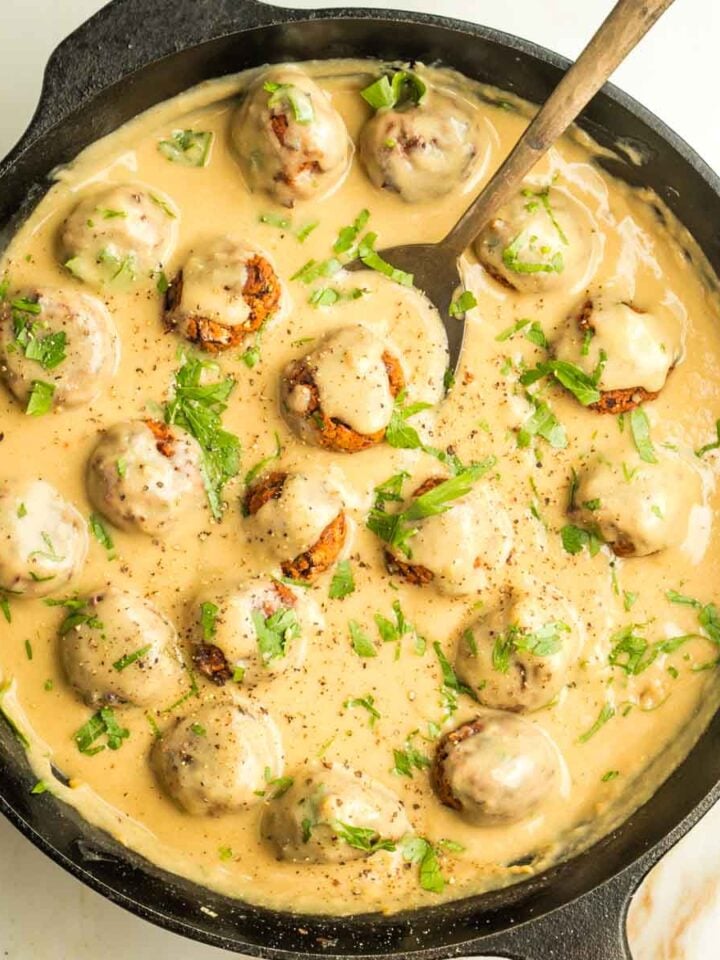 Cast iron pan filled with vegan Swedish meatballs in a creamy sauce.