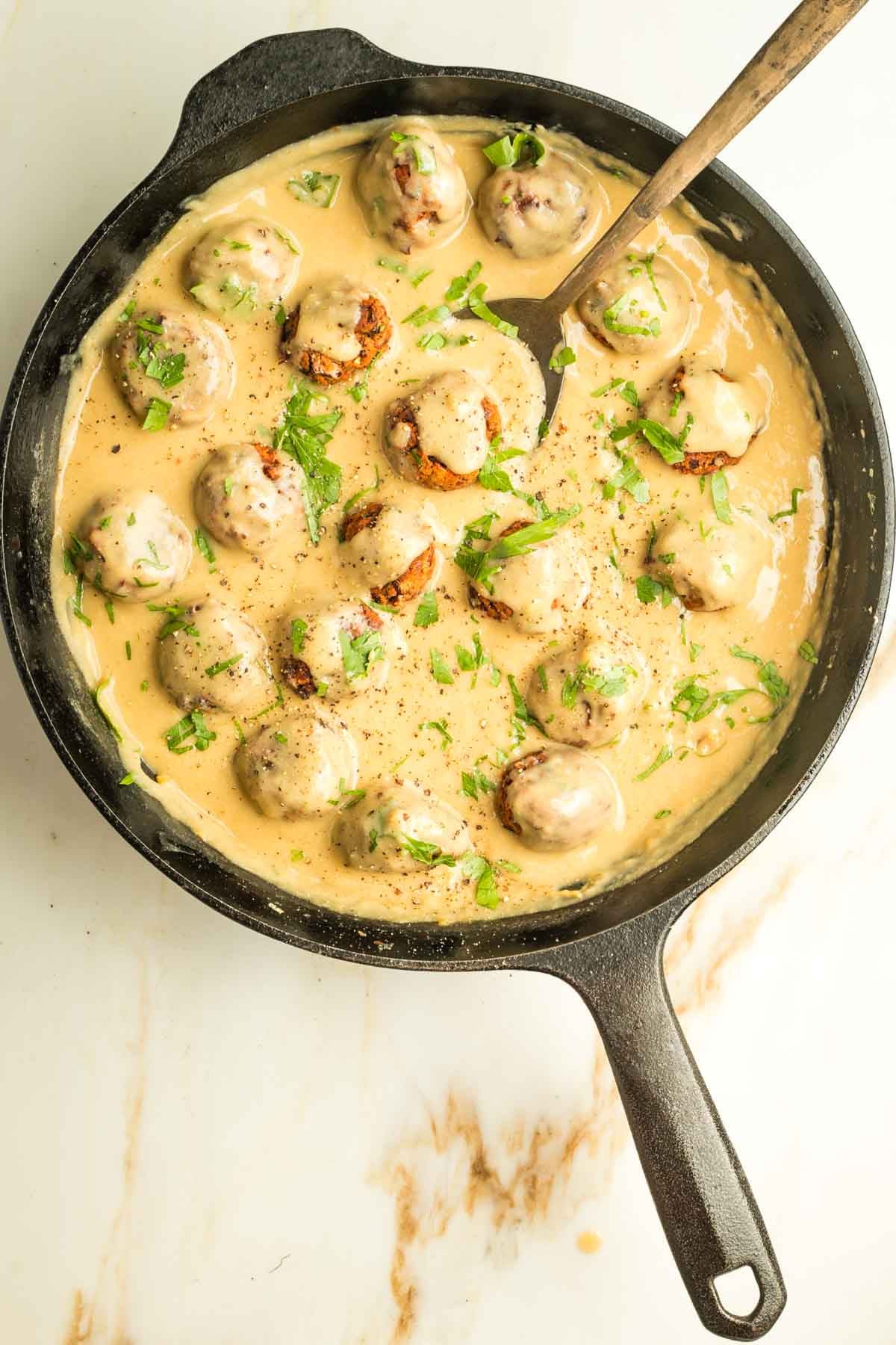 Vegan Swedish meatballs in a mustardy creamy sauce, all inside a cast iron skillet.
