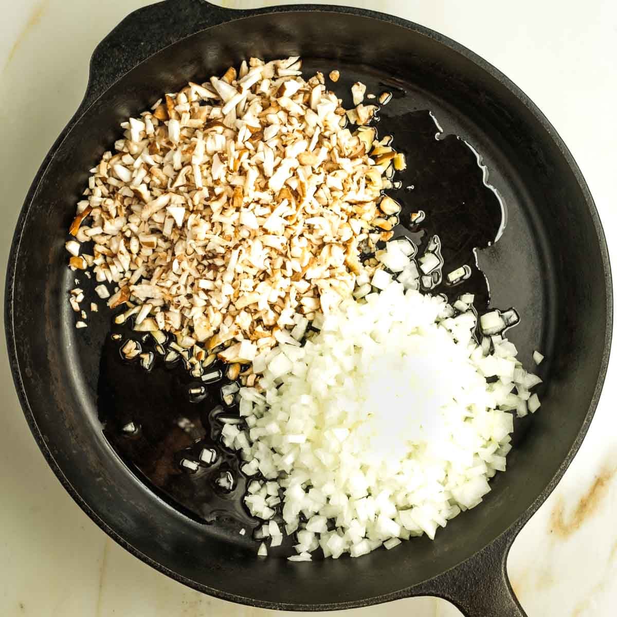 Cast iron skillet with oil, small diced mushrooms and onions.