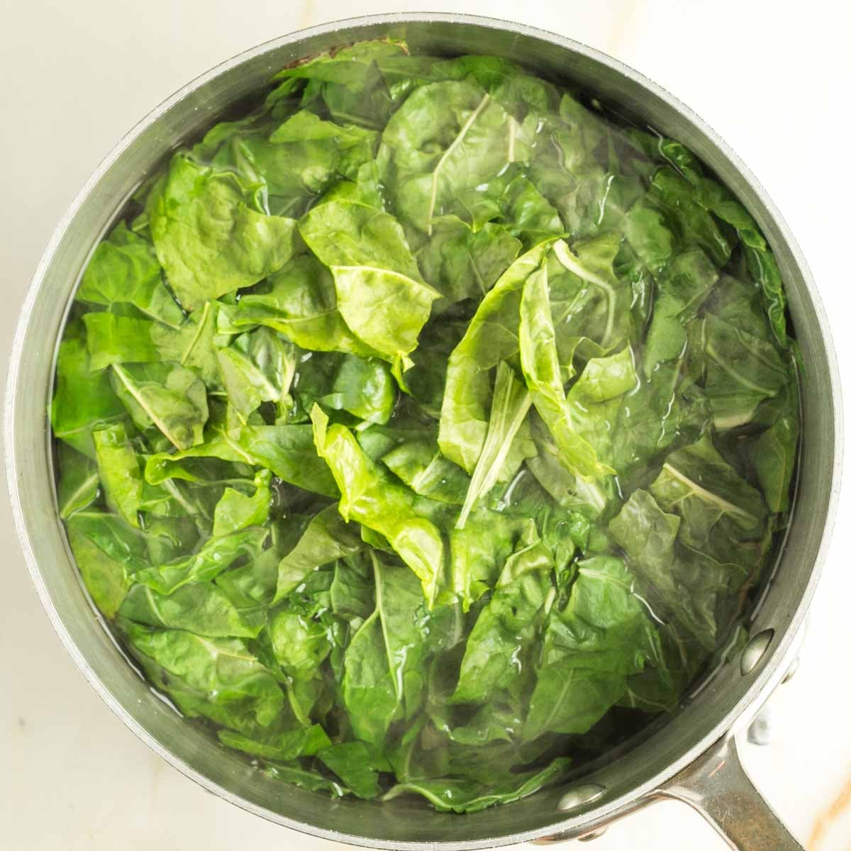 Chard leaves in a pot of boiling water.