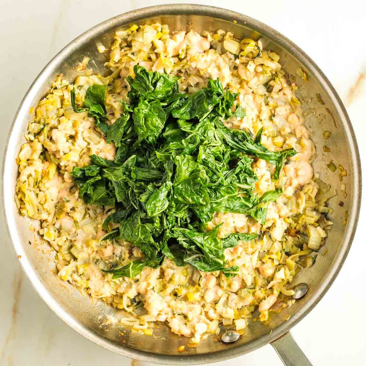 Wilted greens on top of a bean and leek mixture.