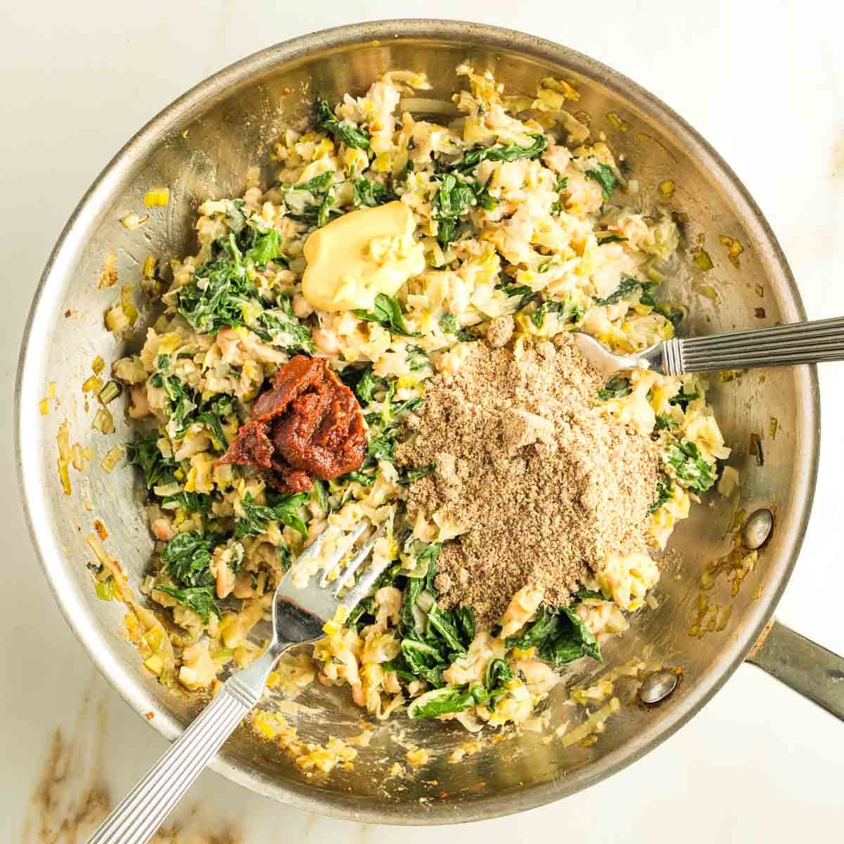 Using two forks to incorporate greens, ground flax, tomato paste and mustard into the leek patty batter. 