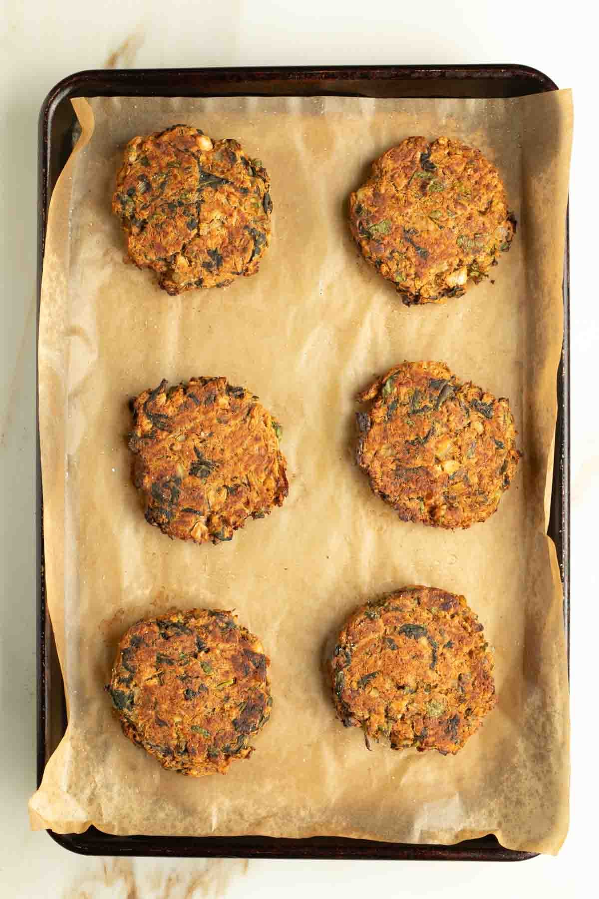 Golden brown leek patties on a baking sheet lined with parchment. 