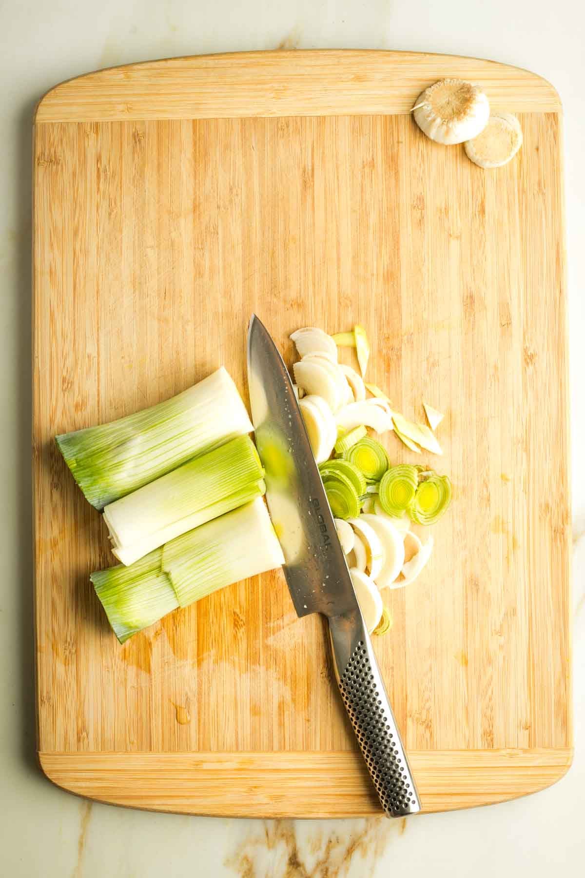 Thinly slicing white and light green parts of leeks that have already been sliced in half lengthwise.