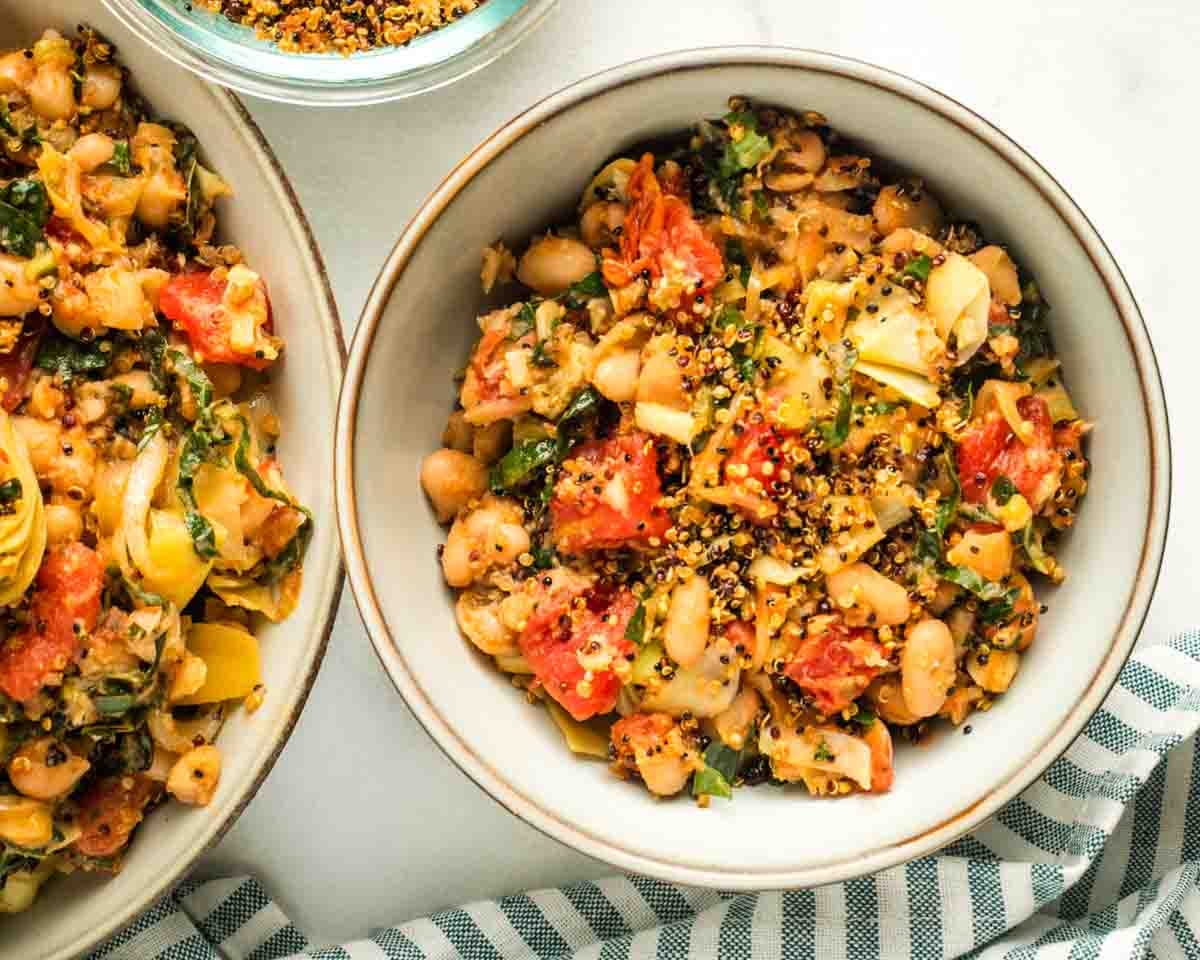 Close up of a bowl of crispy quinoa topped white bean and tomato Tuscan dinner.