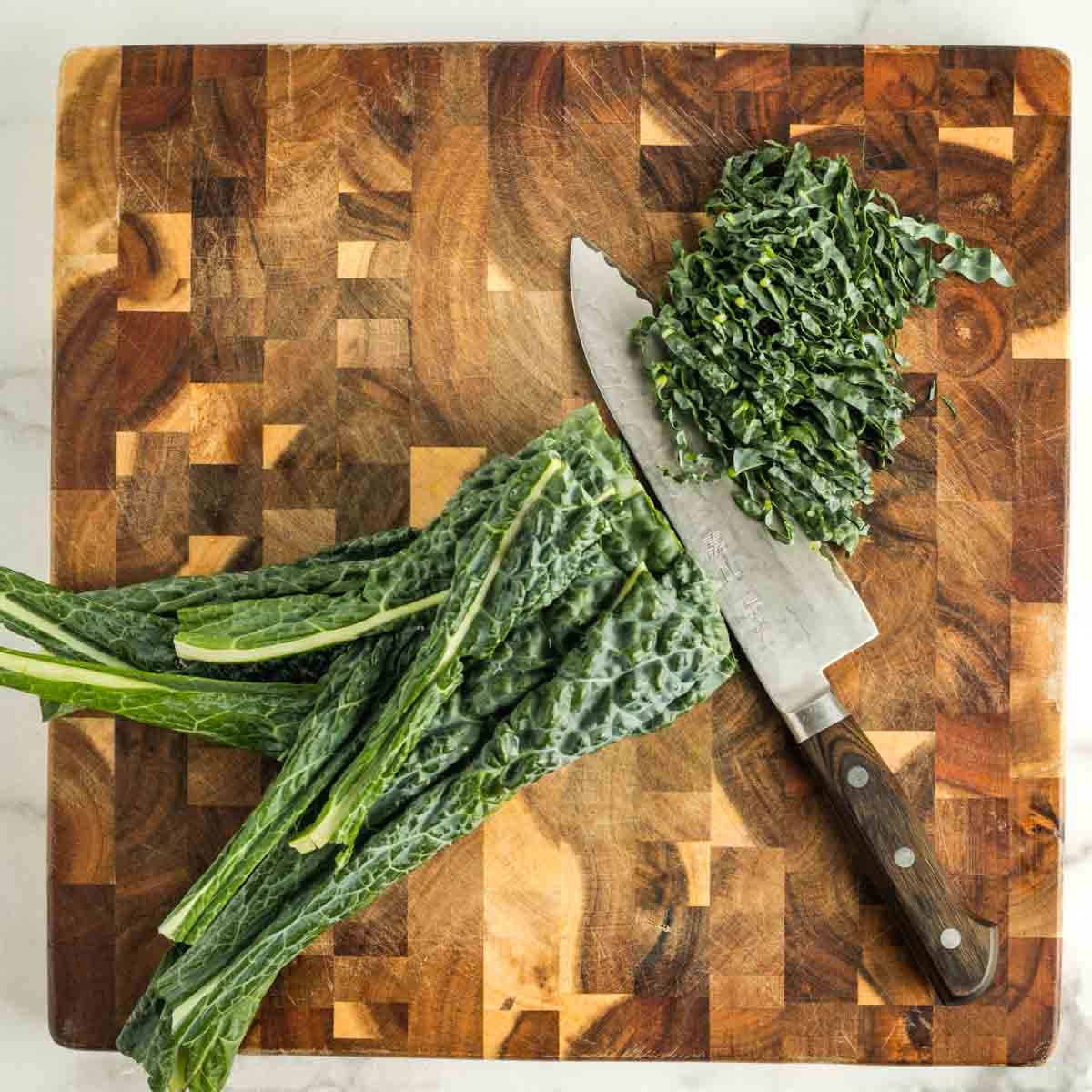 Thinly slicing a stack of lacinato kale leaves. 