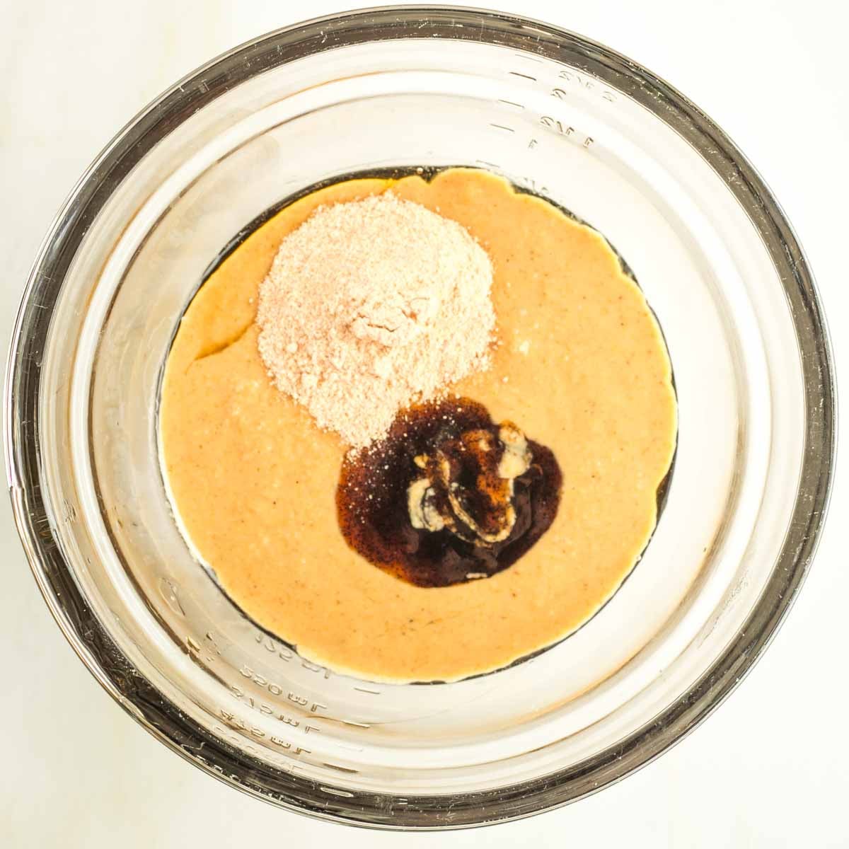 Ingredients in a bowl to make vegan caramel including maple syrup, tahini, date sugar and vanilla paste. 